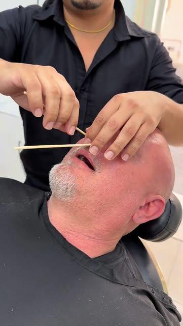 Felo aplicando cera caliente a un cliente