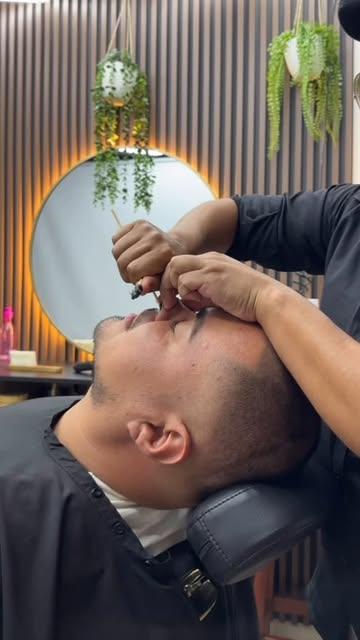 Felo depilando las cejas de un cliente con hilo